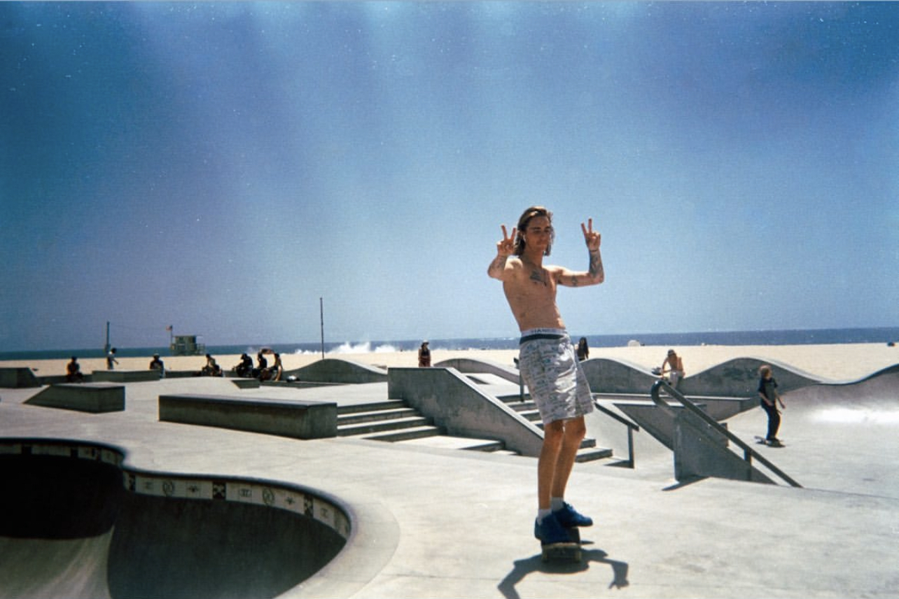 Haden standing on a skateboard at Venice Skatepark.